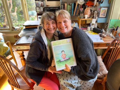 Gracie and Tash smiling and holding an illustration together.